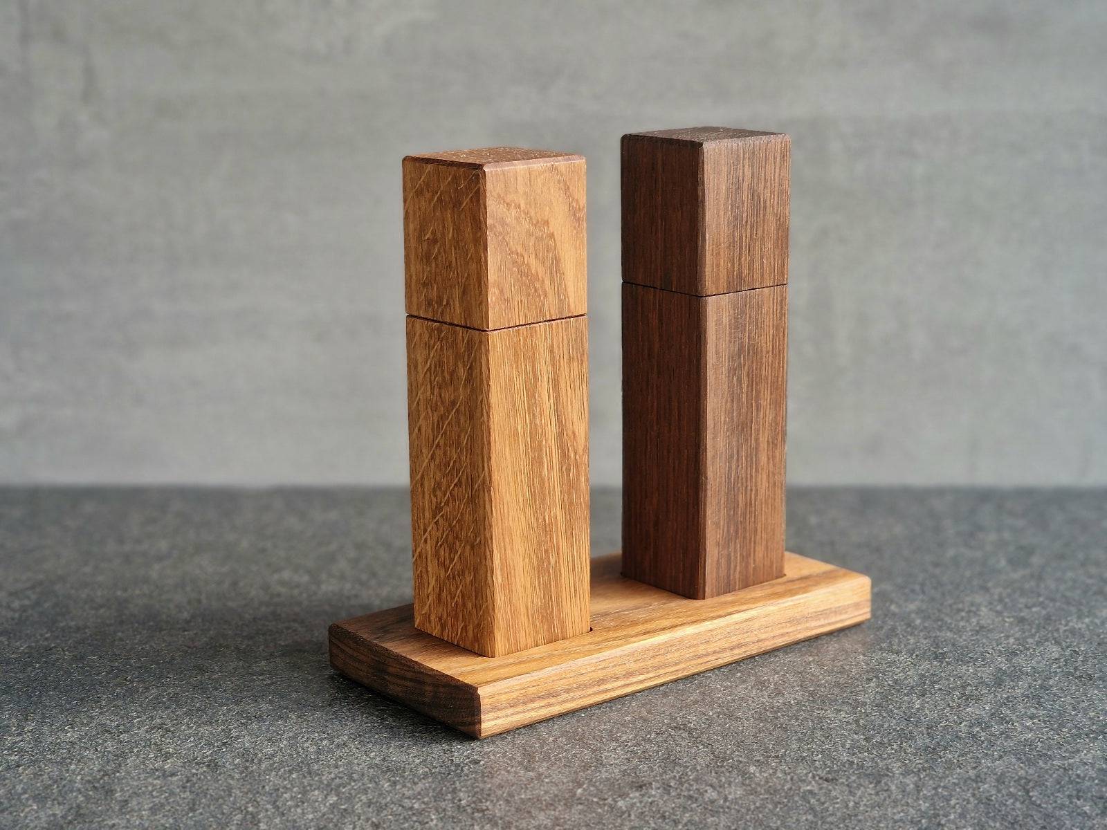 Eiche Salzmühle und Räuchereiche Pfeffermühle auf einem Holz Teller für den Esstisch. Sie sind 20 cm hoch.