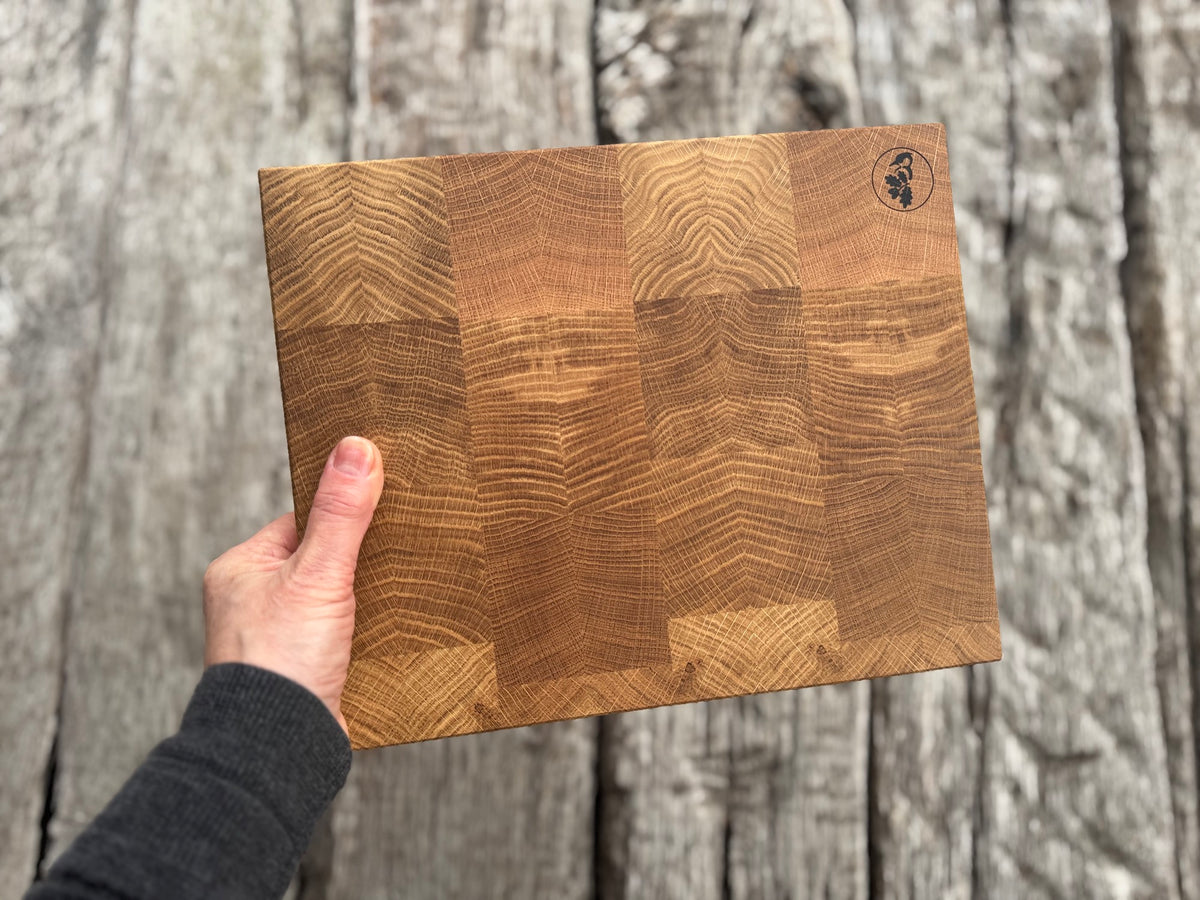 Hand hält 30 cm breites Stirnholz Schneidebrett in die Höhe.