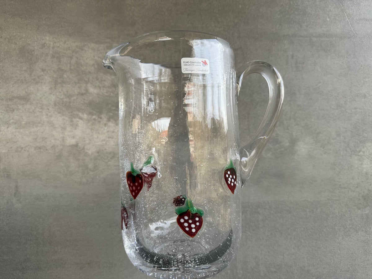 La Fresa Wasserkrug aus Antikglas mit aufgelegten Erdbeeren.
