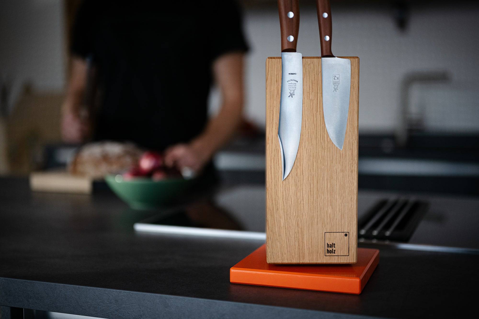 Nahaufnahme von einem magnetischen Messerblock, drehbar aus Eiche mit Stahlsockel in orange.