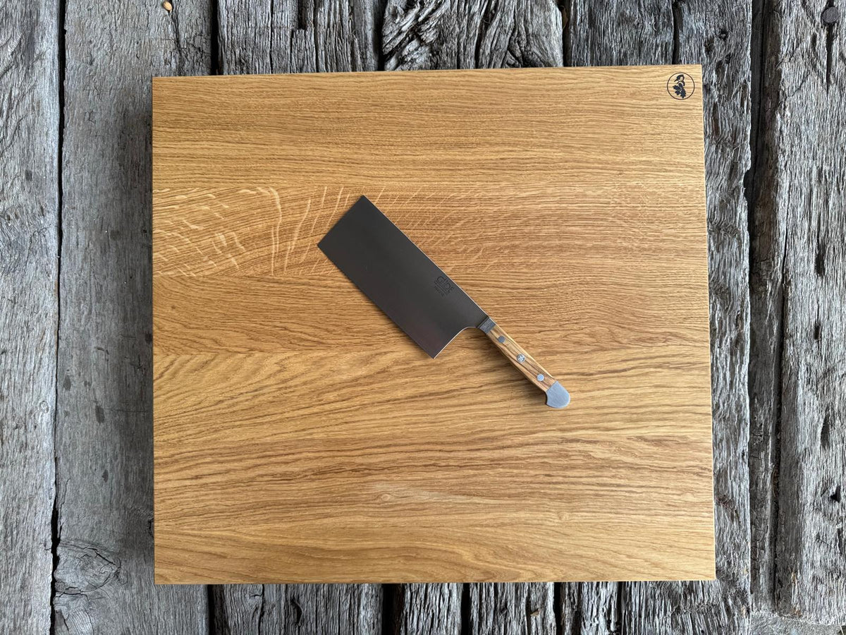 60 cm großer Eiche Schneideblock auf alten Eichenbalken. Dekoriert mit einem Güde Kochmesser Alpha mit Olive Griff.