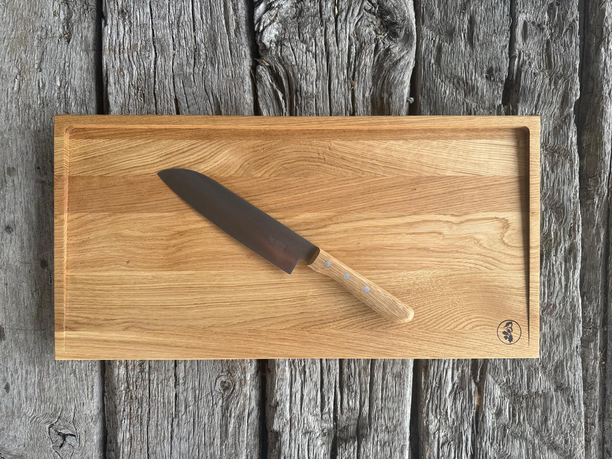 Santoku Kochmesser mit Eiche-Griff auf einem Tranchierbrett 60 cm breit aus Eiche