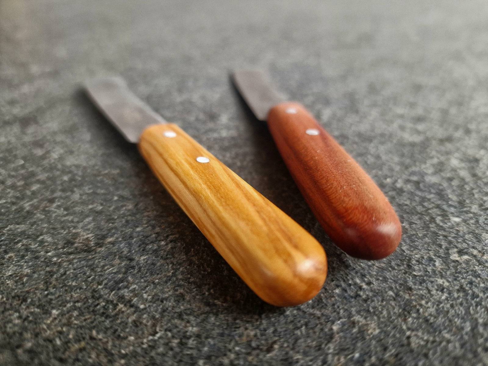 Detailansicht Oliven-Griff und Pflaumen-Griff von einem Buttermesser.
