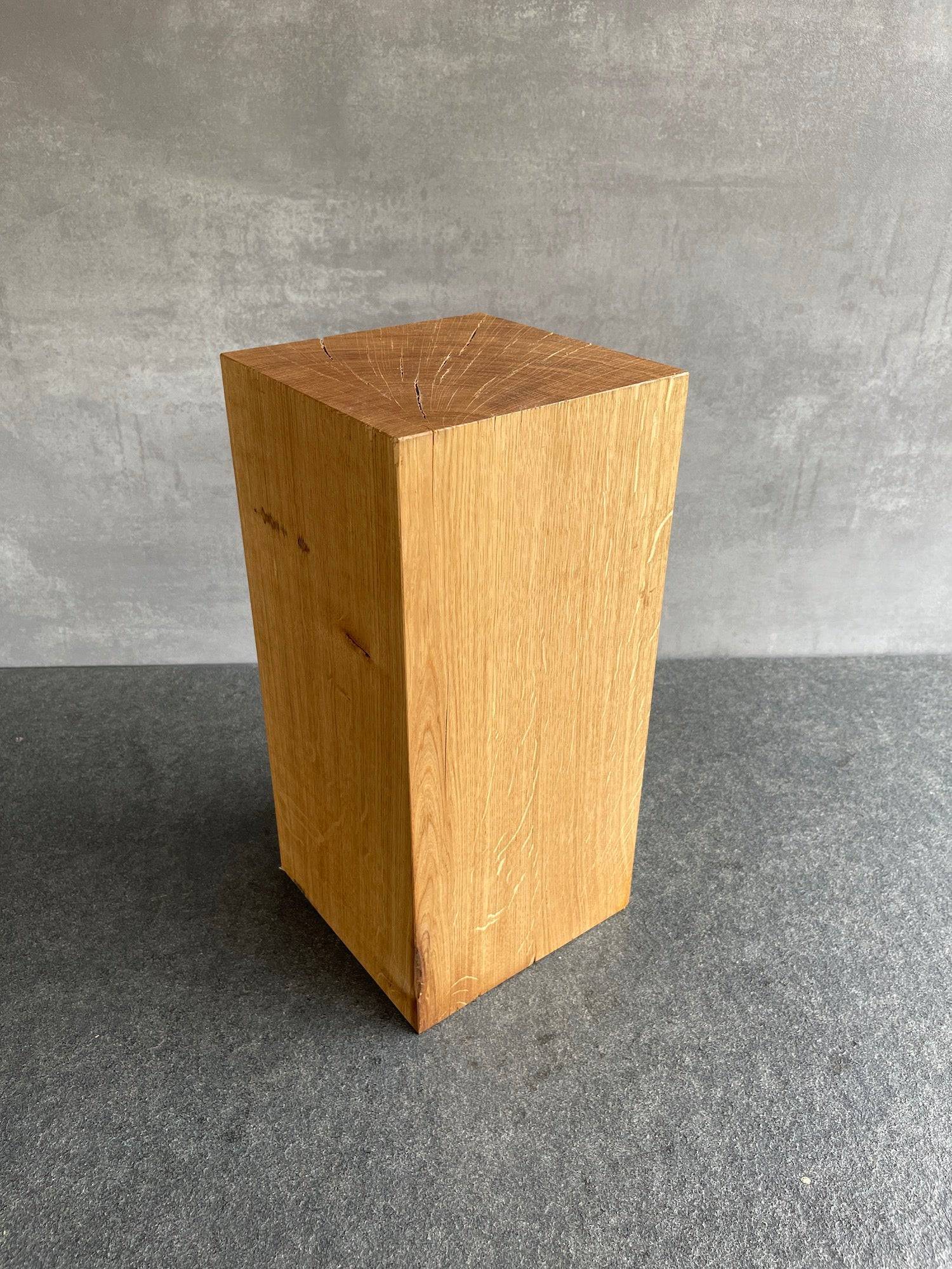Eichenblock 25 cm hoch und 14 mal 14 Zentimeter. Stehend auf einer grauen Arbeitsplatte