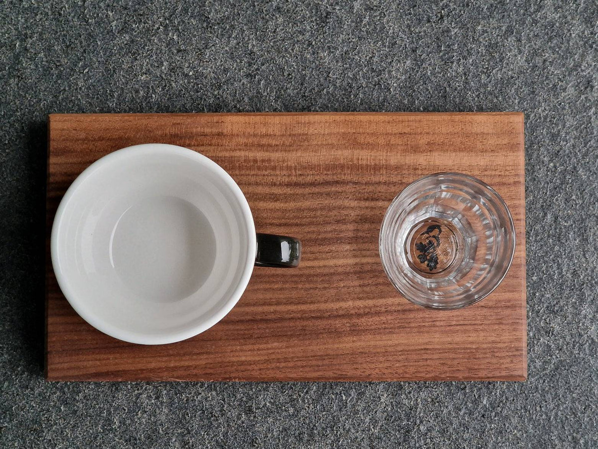 Von oben sieht man ein Nussbaum Tablett mit einer Cappuccinotasse und einem Wasserglas 