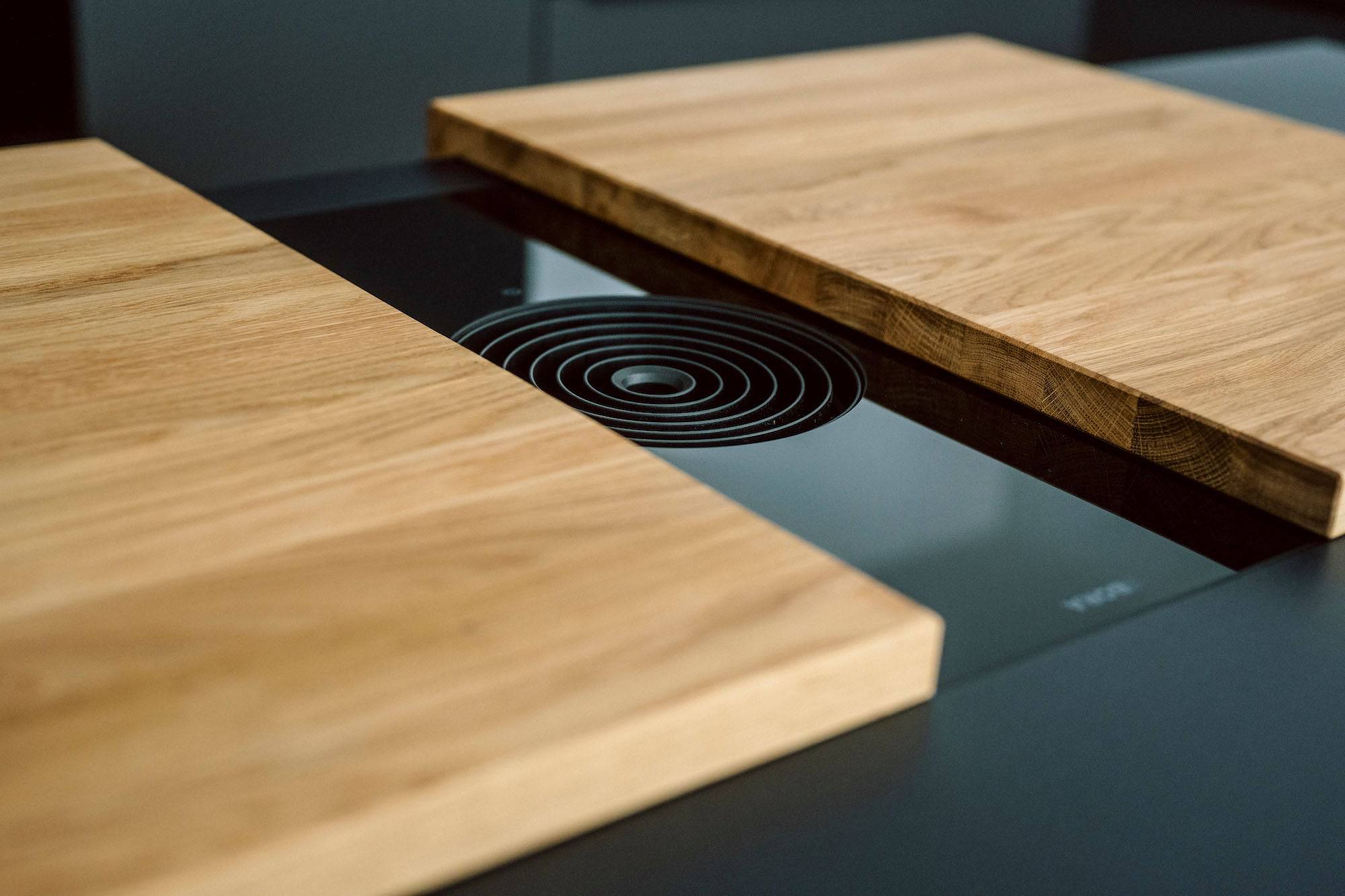 Detailaufnahme eines Bora Kochfeldes auf dem eine zweiteilige Abdeckung  aus Eiche liegt
