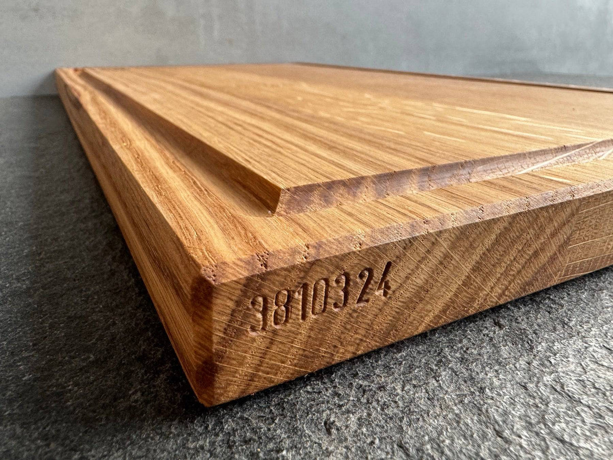 Per Hand eingeschlagene Seriennummer bei einem 50 cm breiten Saftrillen Schneidebrett aus massiver Eiche.