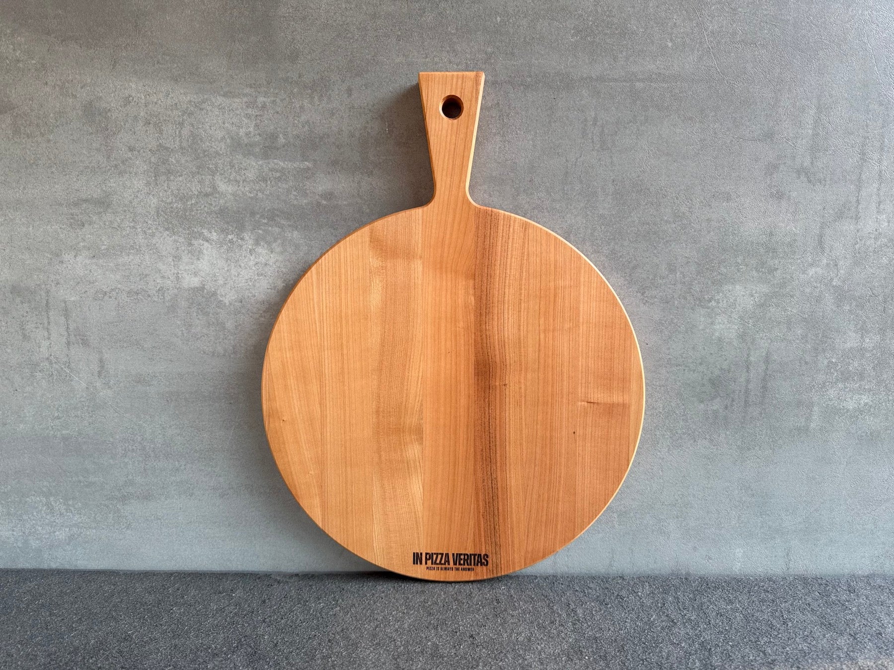Pizzabrett mit Stielgriff aus Kirschholz – leicht zu tragen und zu servieren.
Mit Gravur: „In Pizza Veritas. Pizza is always the answer.“