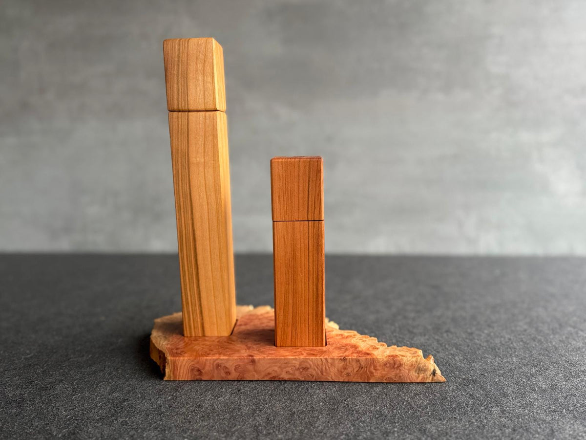 28 cm Pfeffermühle und 18 cm Salzmühle aus massivem Kirschbaum an einer Betonwand.