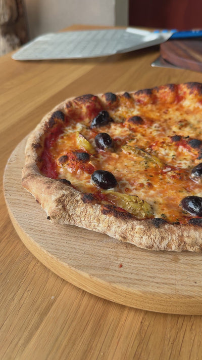 Pizza die auf Pizzabrett von Spessartbrett geschnitten wird