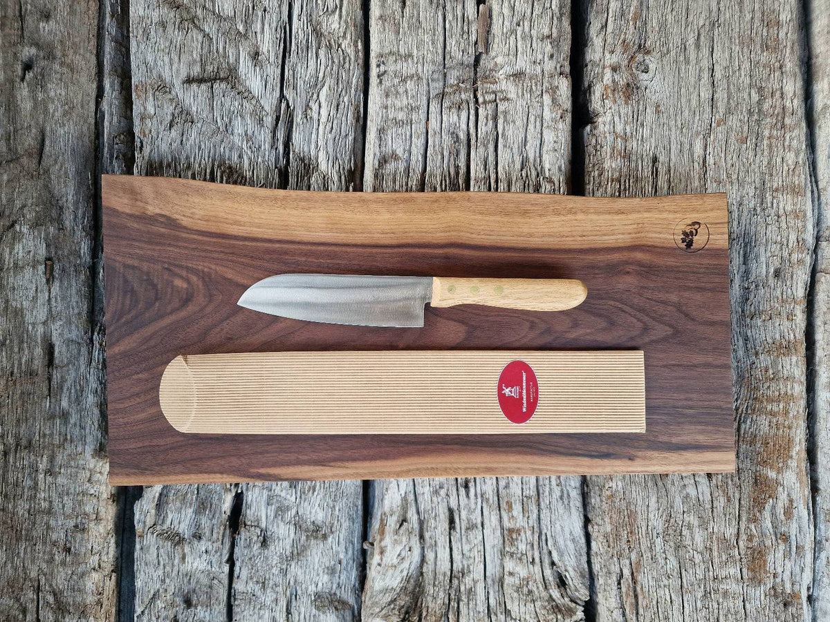 Geschenkset Vollholz Schneidebrett aus massivem Nussbaum mit Santoku Kochmesser mit Eiche Griff, fotografiert auf historischen Eichenbalken.