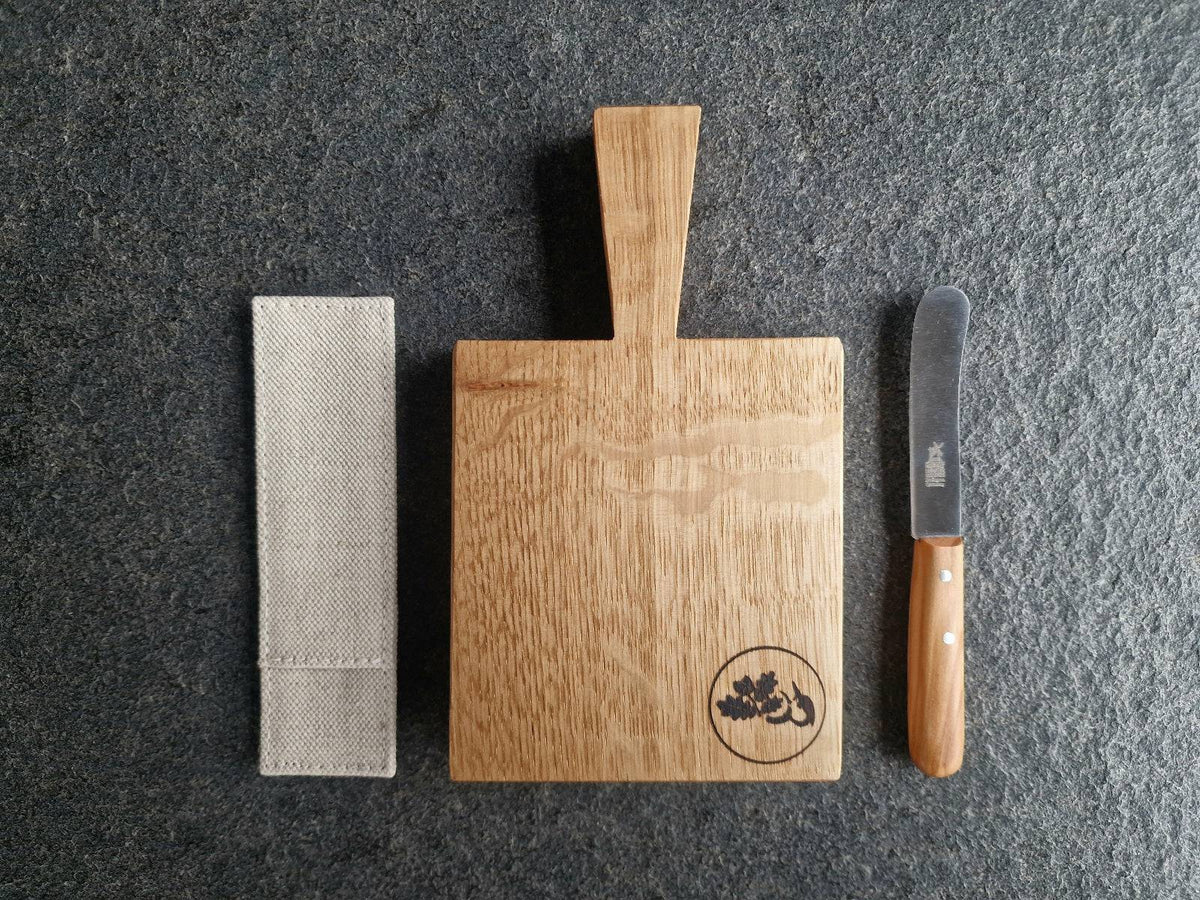 Kräuterbutter Brett in der Mitte. Links ein Windmühlenmesser Leinen Etui. Rechts ein Windmühlenmesser Beilegemesser.