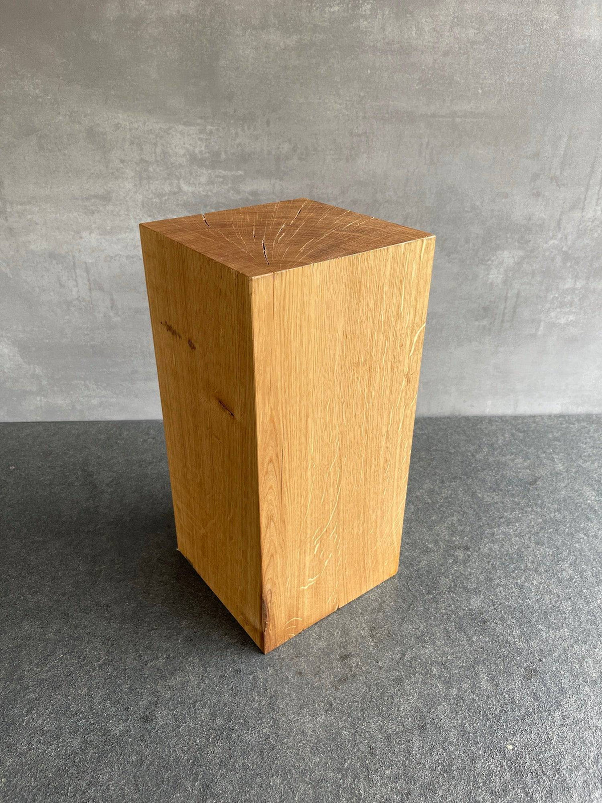 Eichenblock 25 cm hoch und 14 mal 14 Zentimeter. Stehend auf einer grauen Arbeitsplatte